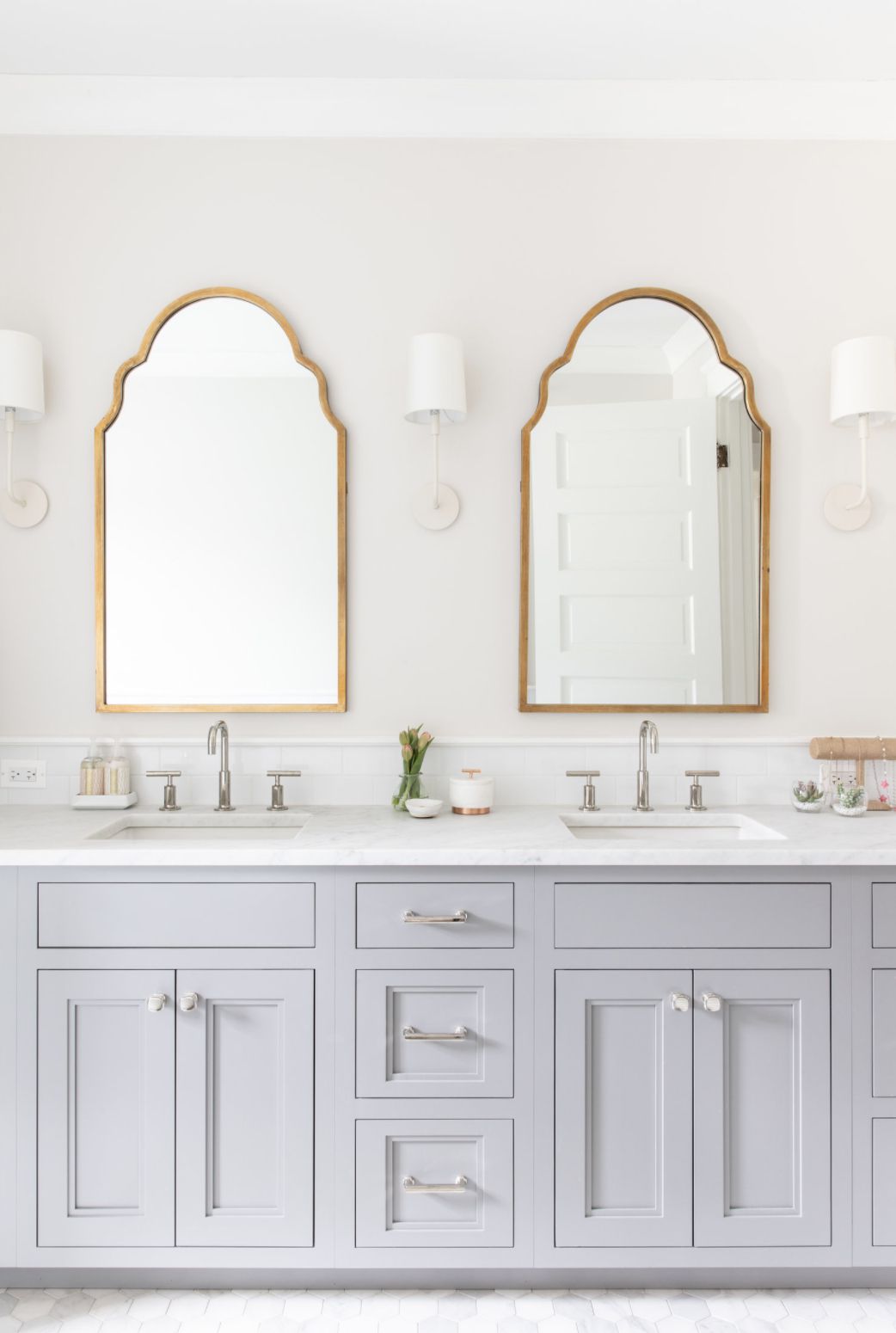 hellgraue Schränke und weiße Wände Badezimmer mit Doppelwaschtisch und goldenen Spiegeln