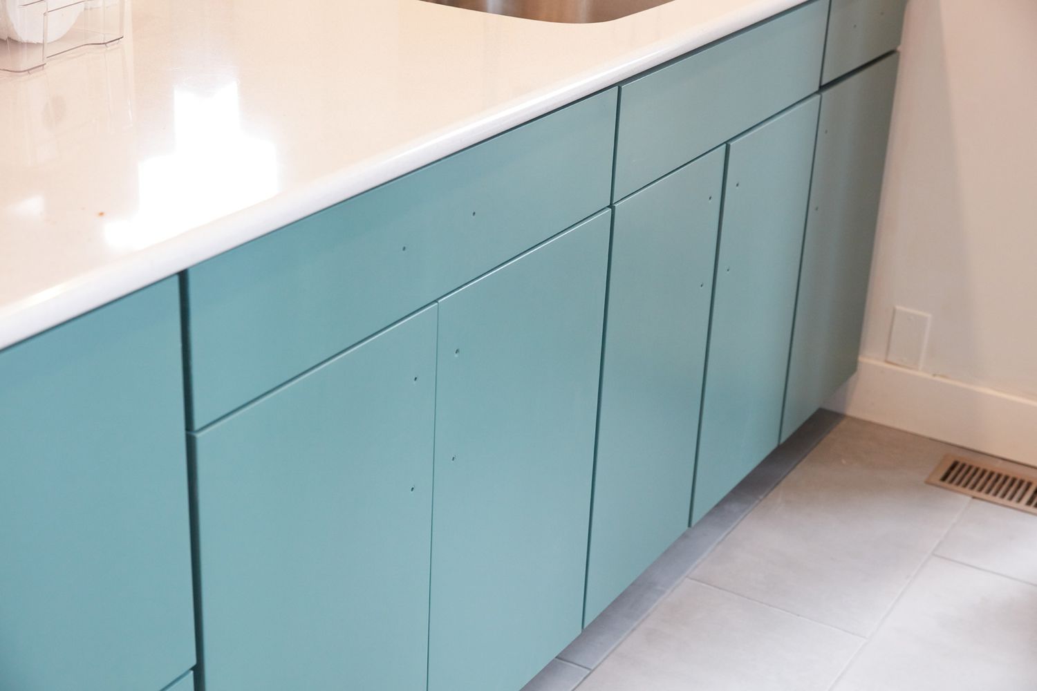 Küchenschränke mit mintgrüner Farbe unter weißer Arbeitsplatte