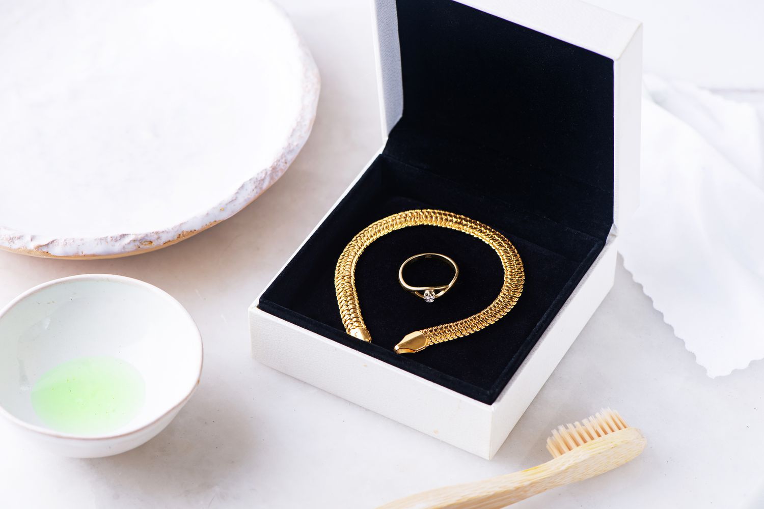 Goldarmband und -ring in schwarzer Schachtel neben Zahnbürste und Geschirrspülmittel