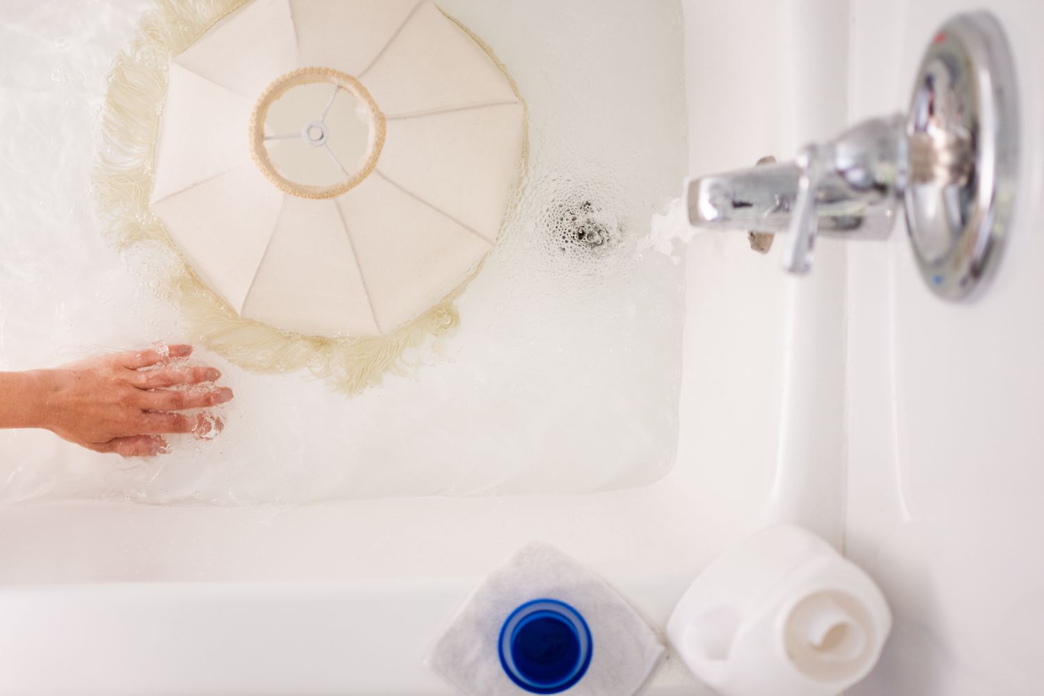 Abajur branco colocado na banheira com água doce para ser enxaguado