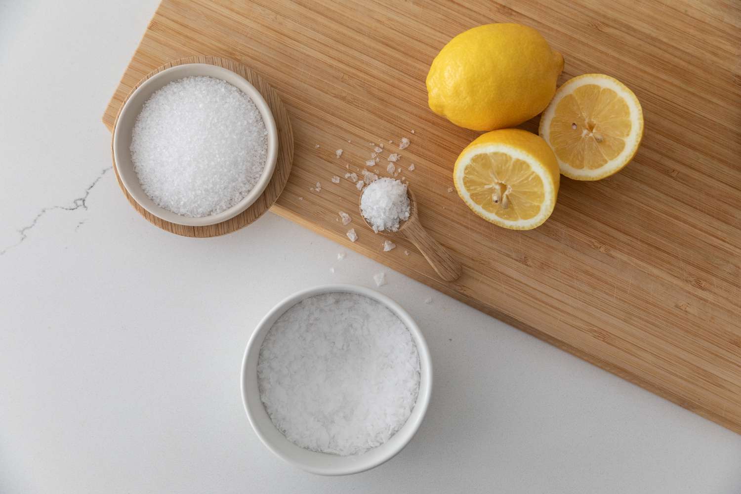 Schneidebrett mit aufgeschnittenen Zitronen und Salzschalen mit Löffel voll Salz