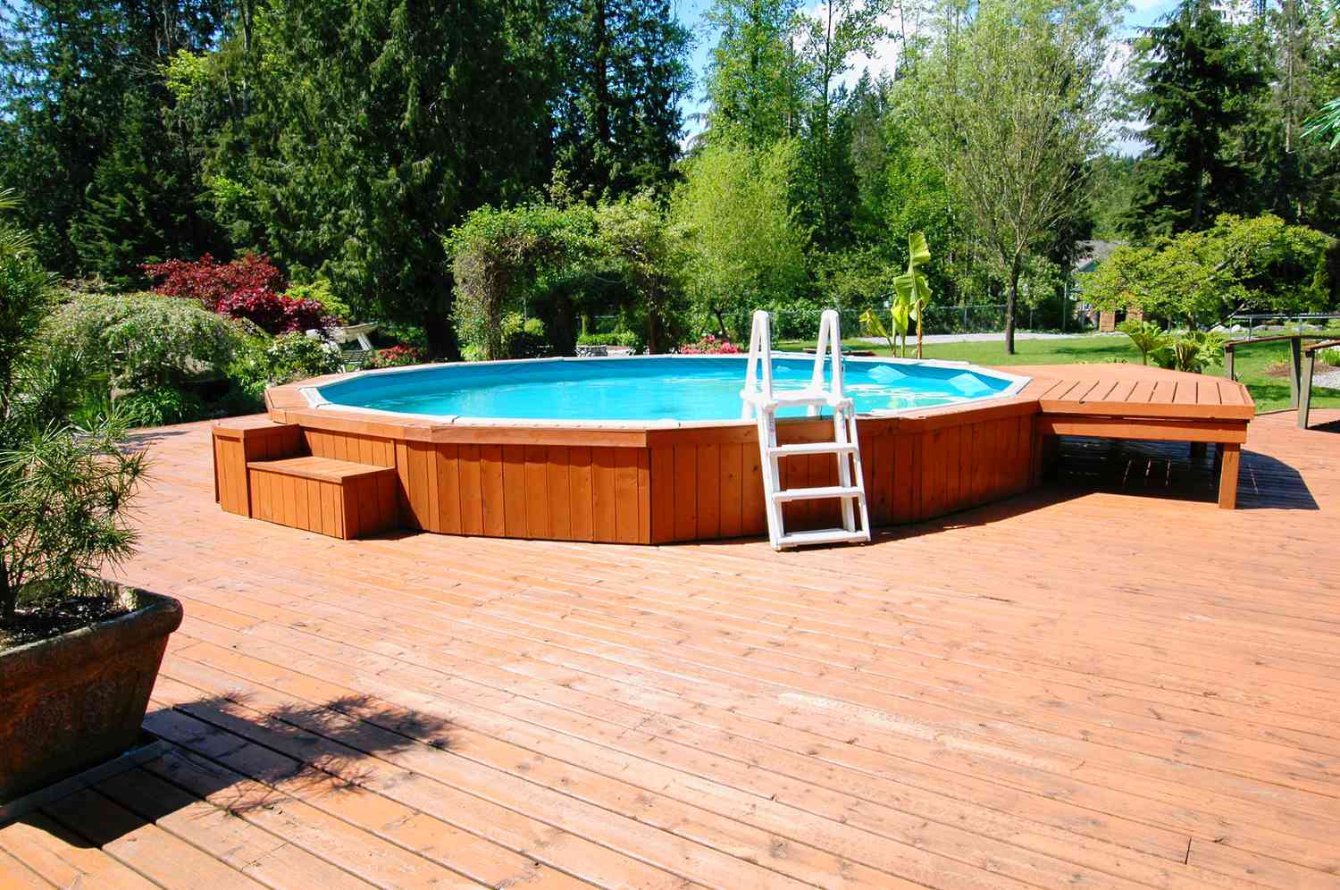 Uma piscina acima do solo em um grande deck com escada branca.