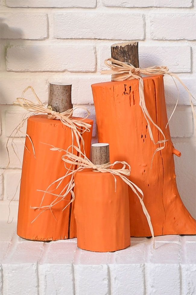 Tocones de árbol pintados de naranja y decorados como una calabaza