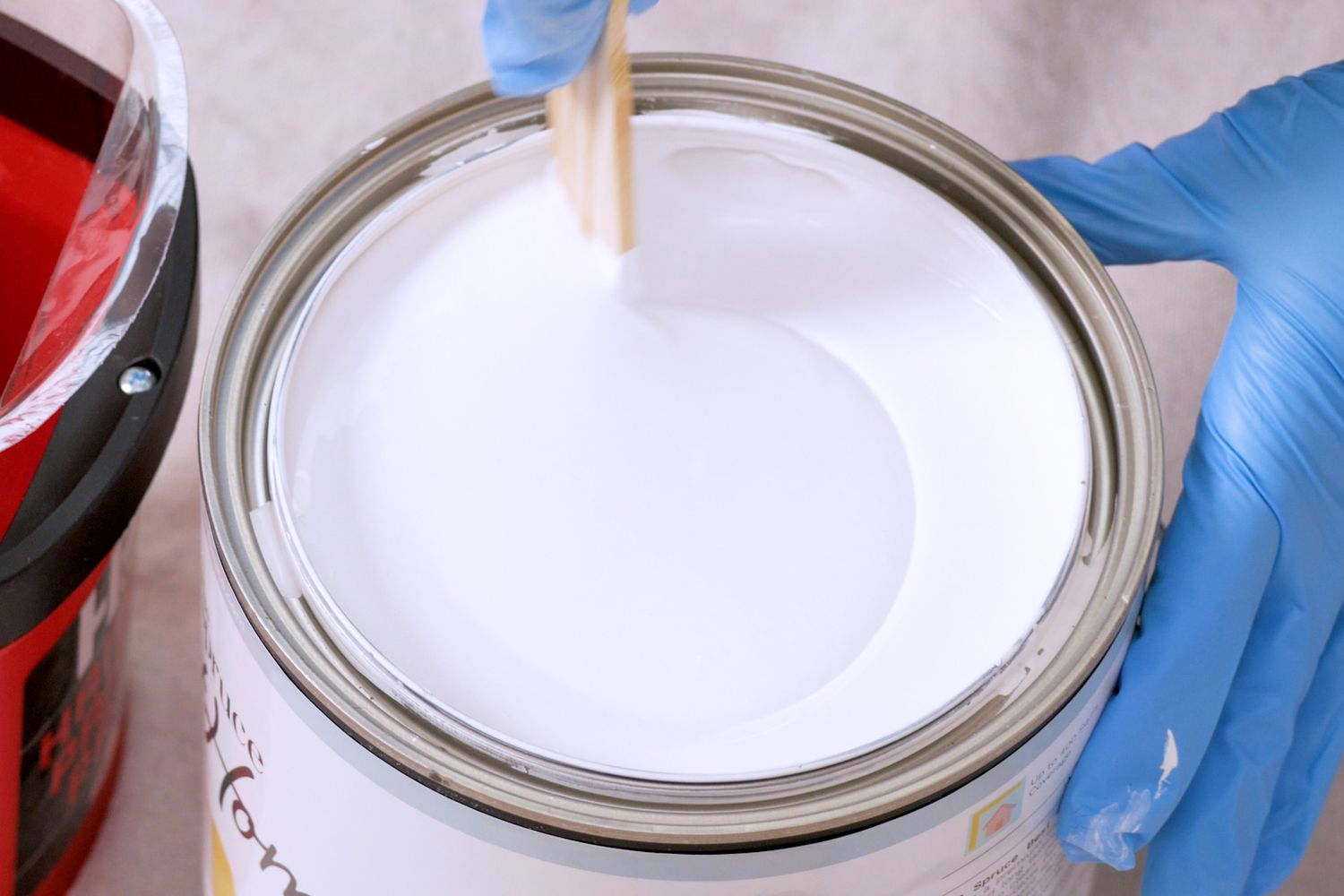 Primer in bucket being stirred by hand with blue gloves