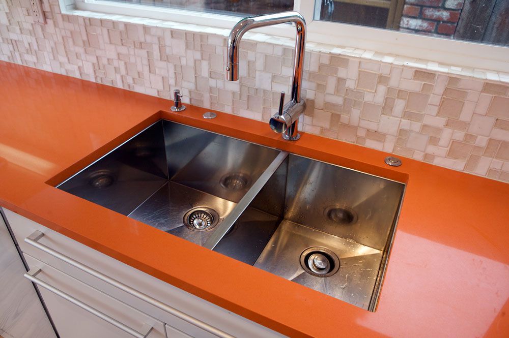 Orangefarbene Quarz-Küchenarbeitsplatte mit Spülbecken.