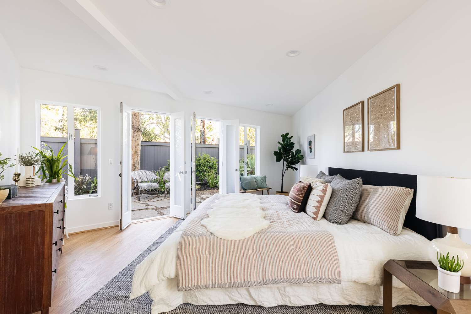 Grande chambre à coucher avec des murs blancs et de grandes fenêtres ouvertes sur le jardin