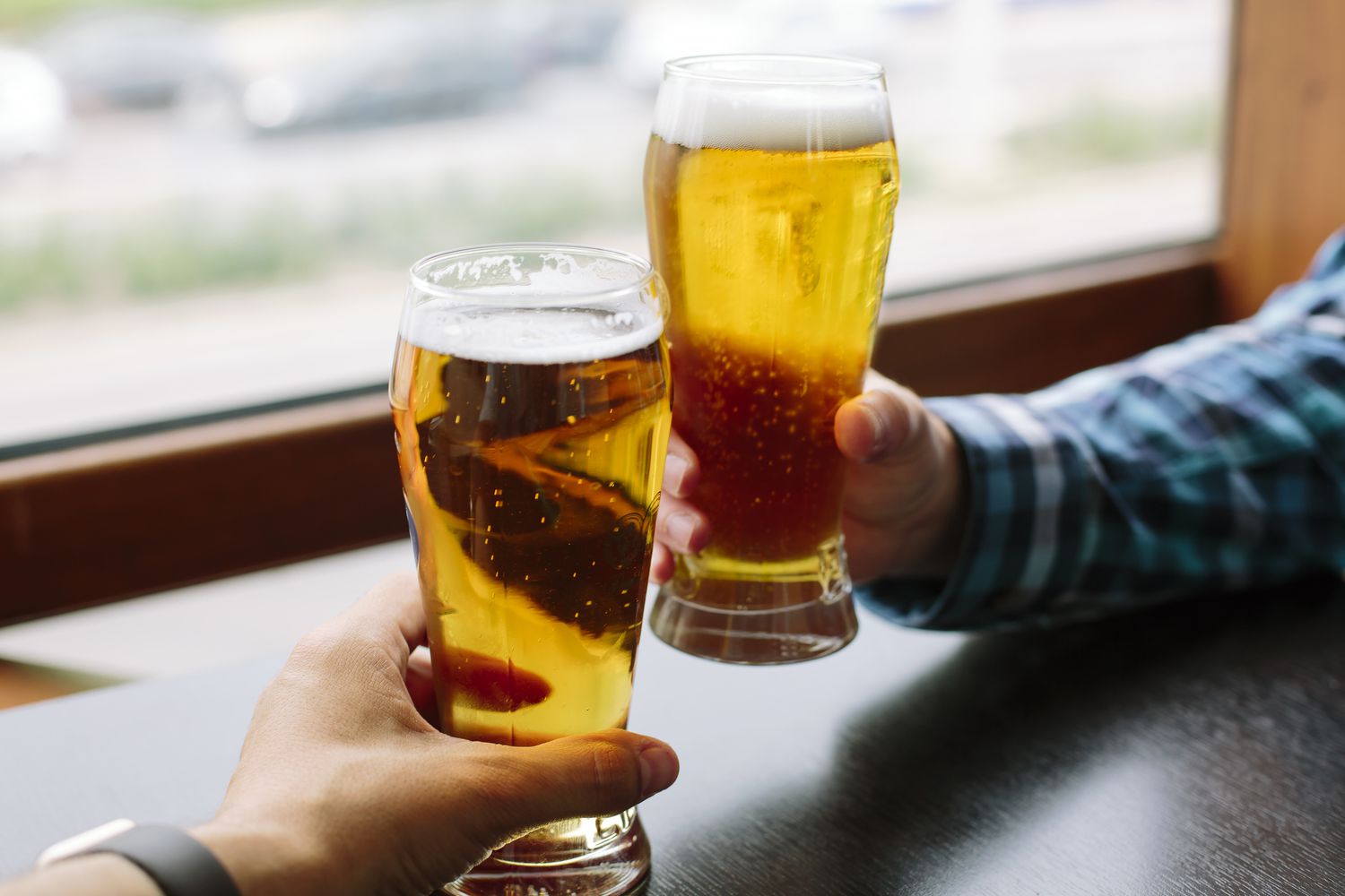 Zwei Freunde stoßen mit einem Glas Bier an.