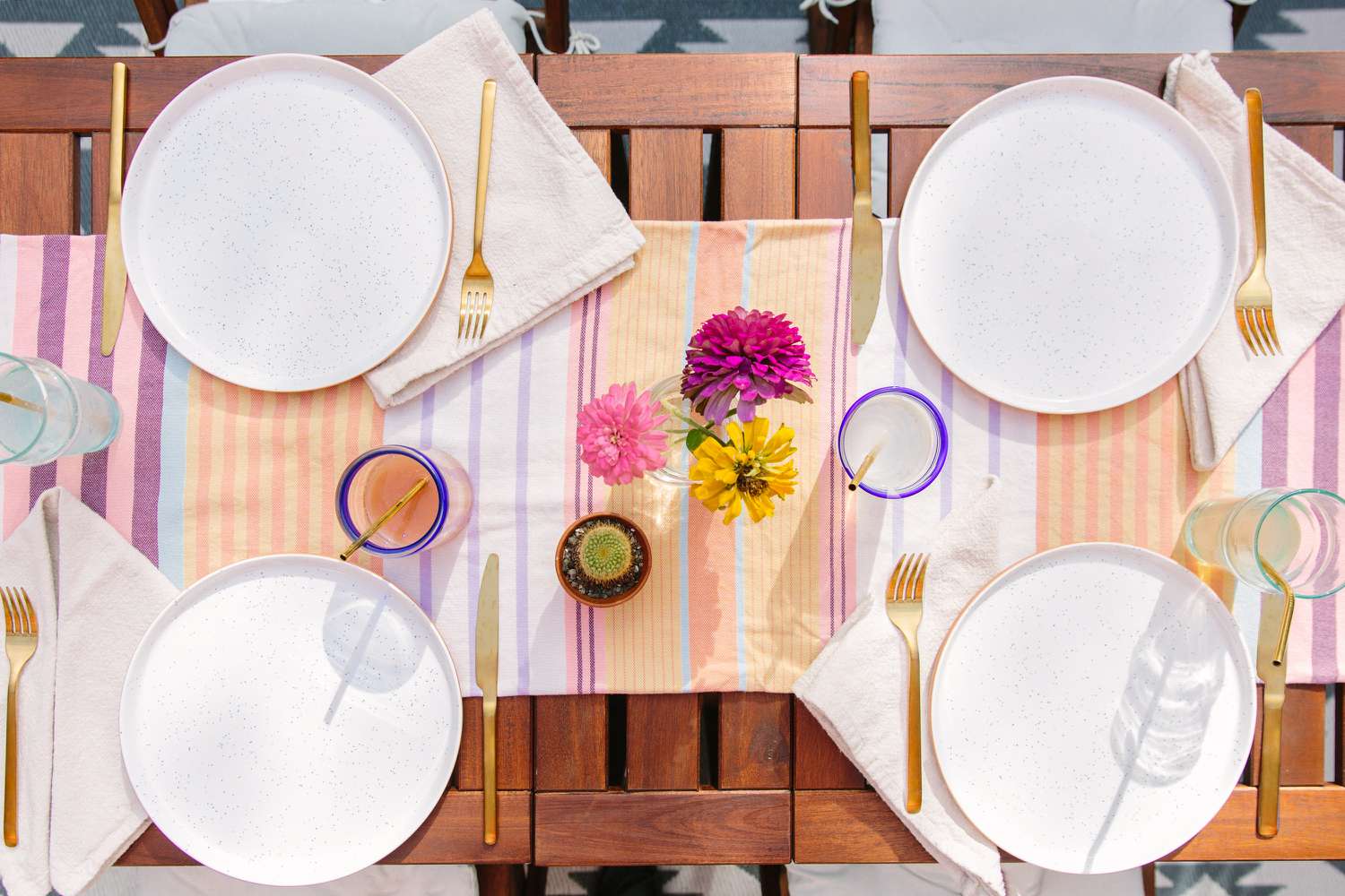 Assiettes, boissons, et un centre de table en fleurs colorées sur une table en bois