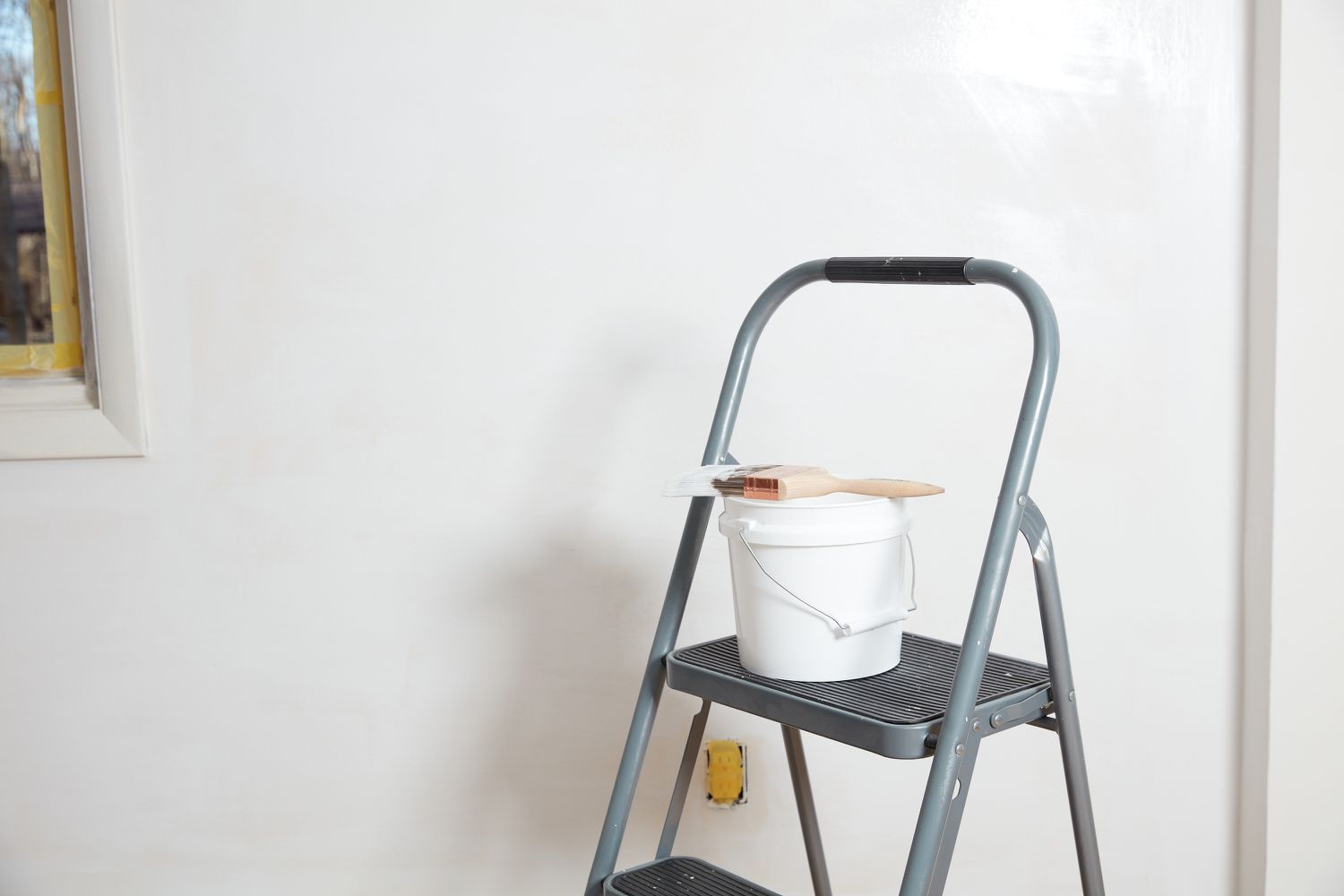 Painted wall drying with ladder and paint bucket in front