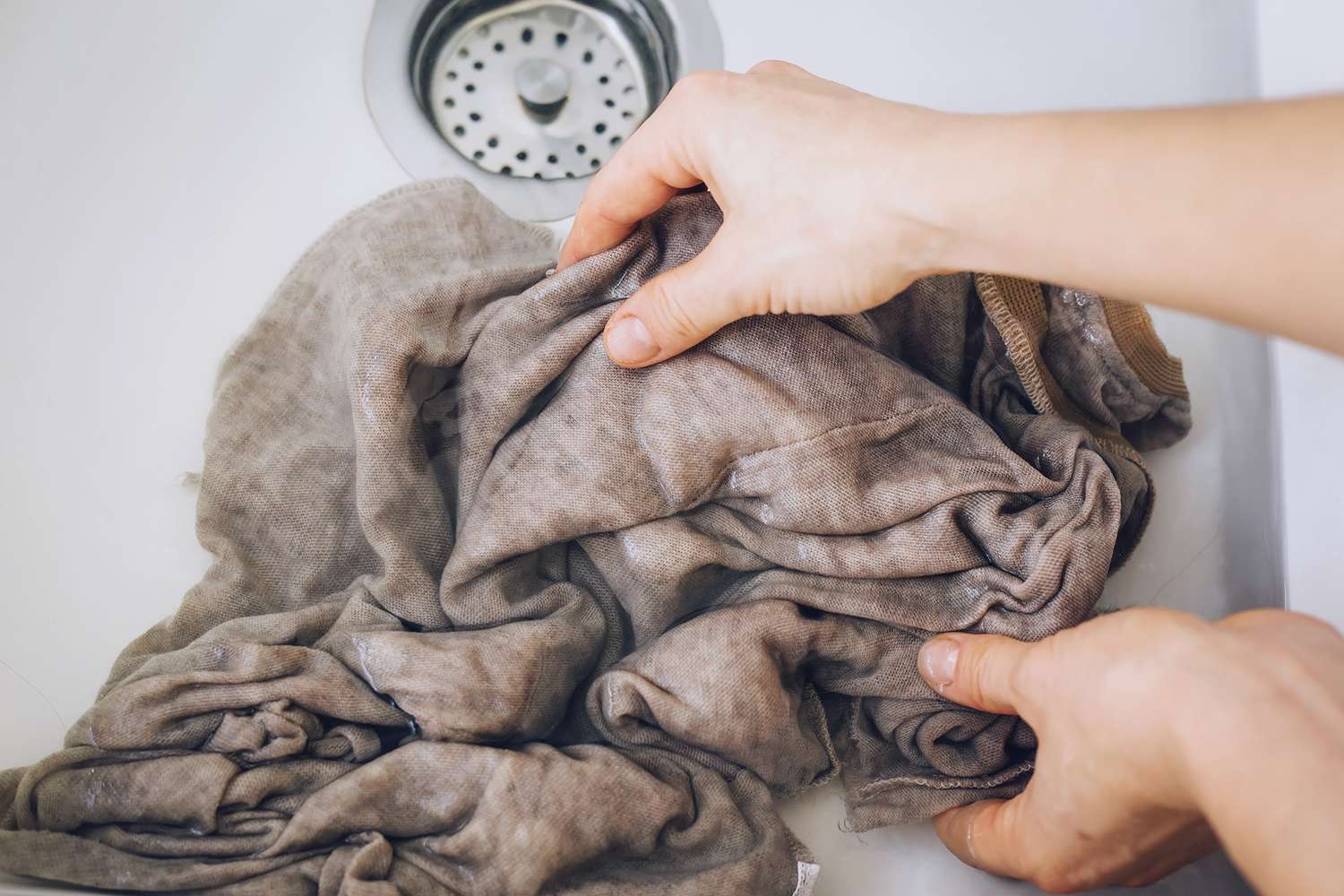 Alguém drenando uma pia com uma peça de roupa molhada dentro