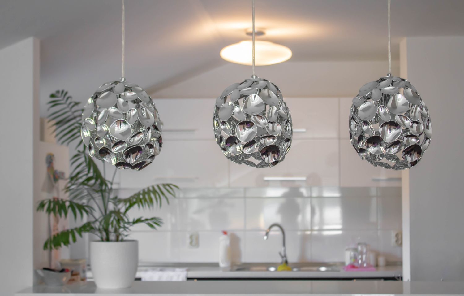 Tres modernas lámparas colgantes metálicas colgando delante de la cocina