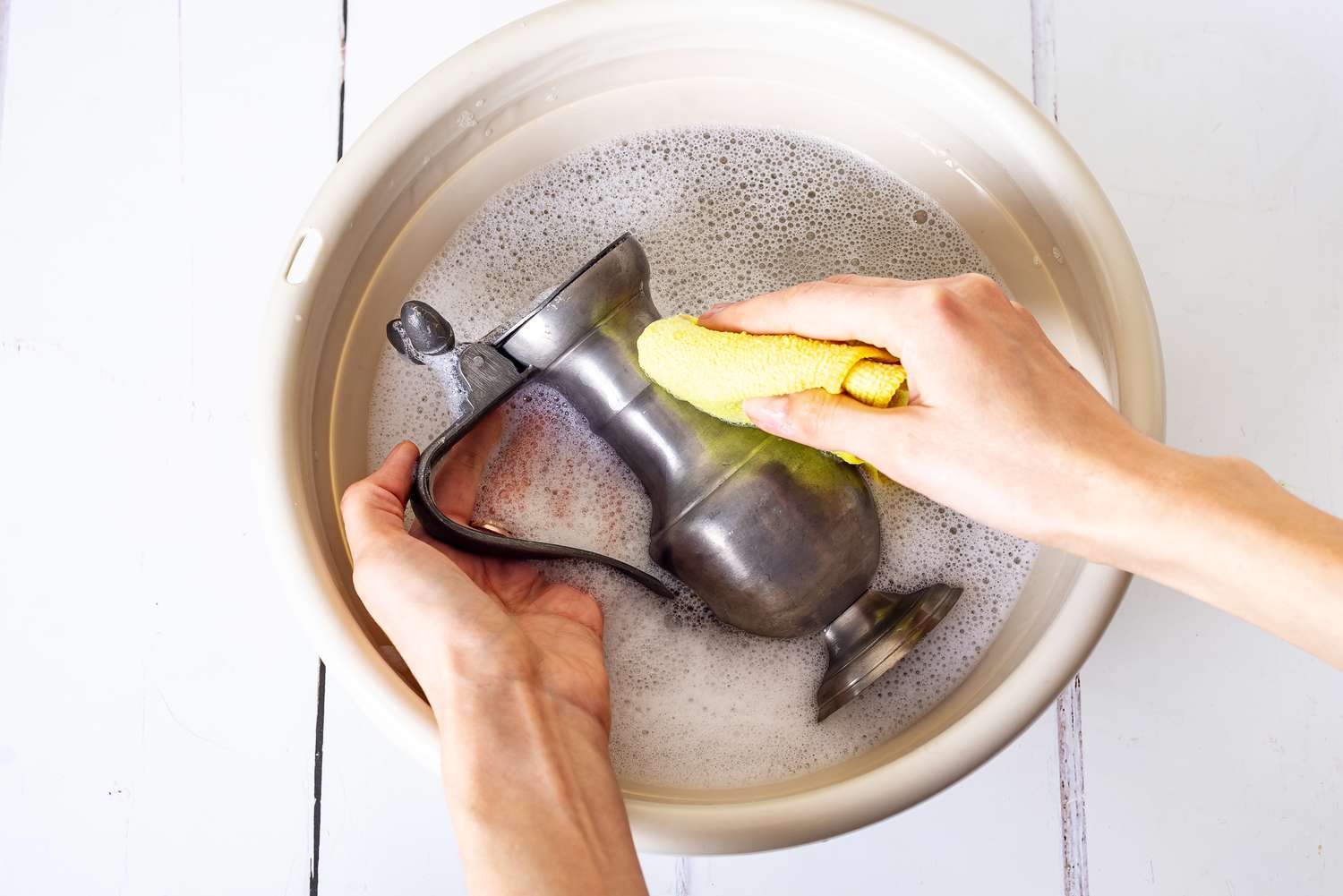 Zinnspender mit gelbem Tuch in mit Reinigungslösung gefülltem Eimer gewaschen