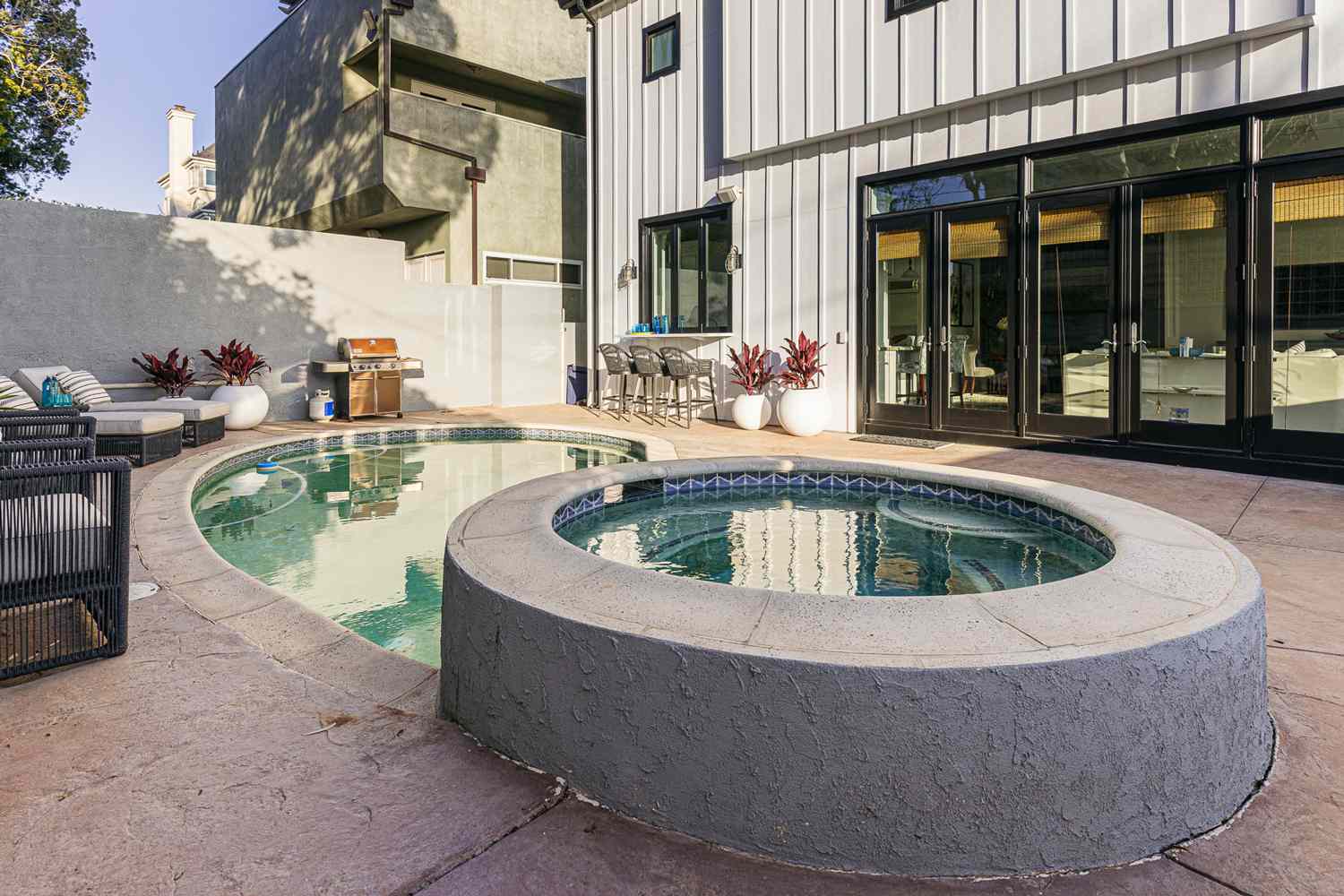 Runde, mit Beton umgebene Badewanne neben kleinem Pool