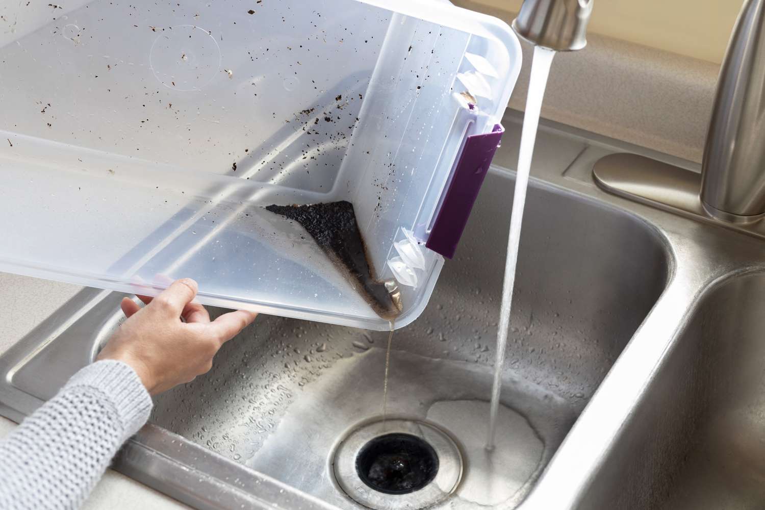 Kompostbehälter in der Küchenspüle unter fließendem Wasser geleert und gereinigt