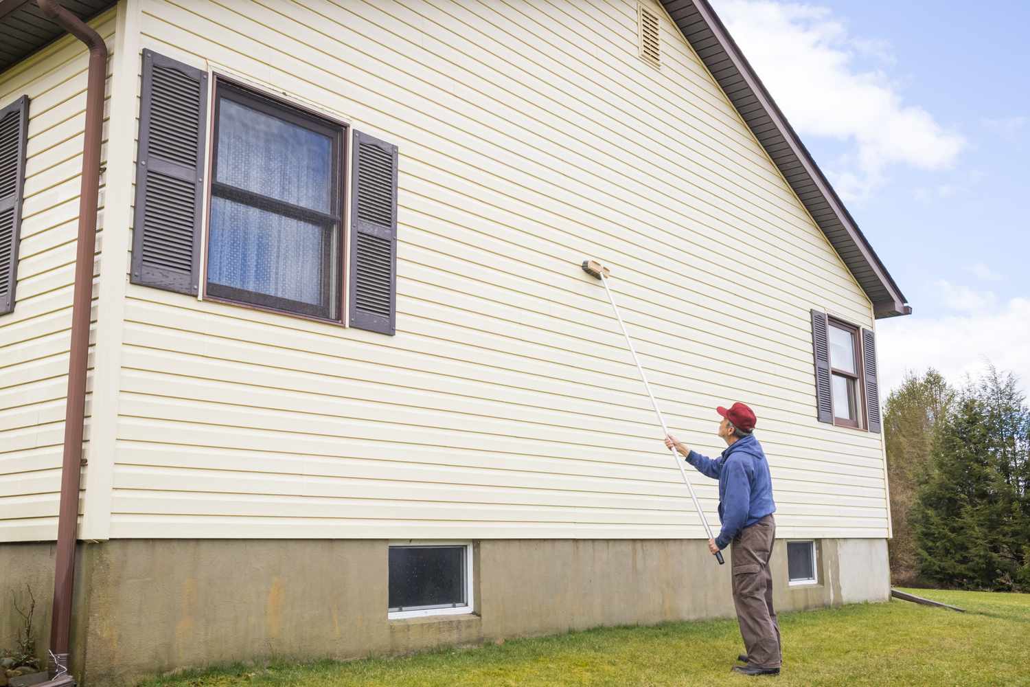 Hombre lavando el revestimiento de una casa