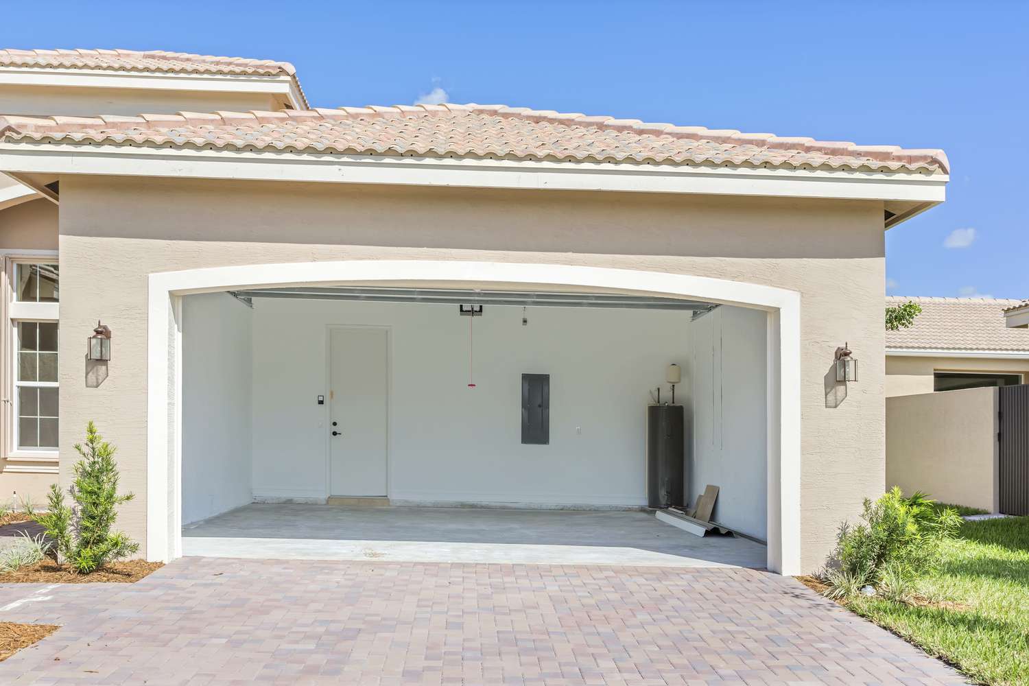 garage et allée d'une maison beige clair avec la porte de garage ouverte et l'intérieur vide