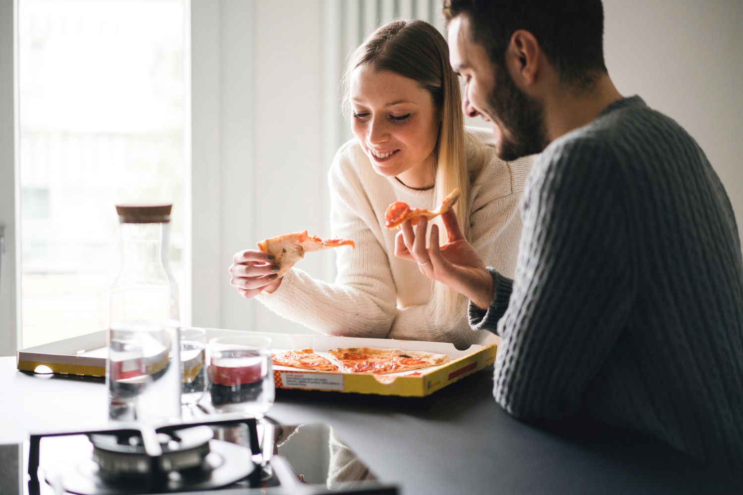 Ein Paar isst Pizza in der Küche.