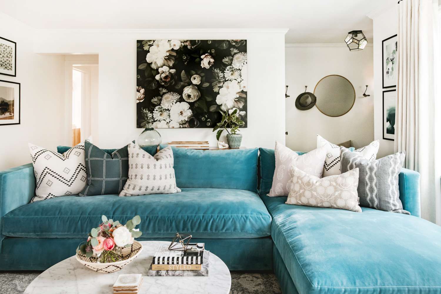 Teal velvet sofa with neutral throw pillows.