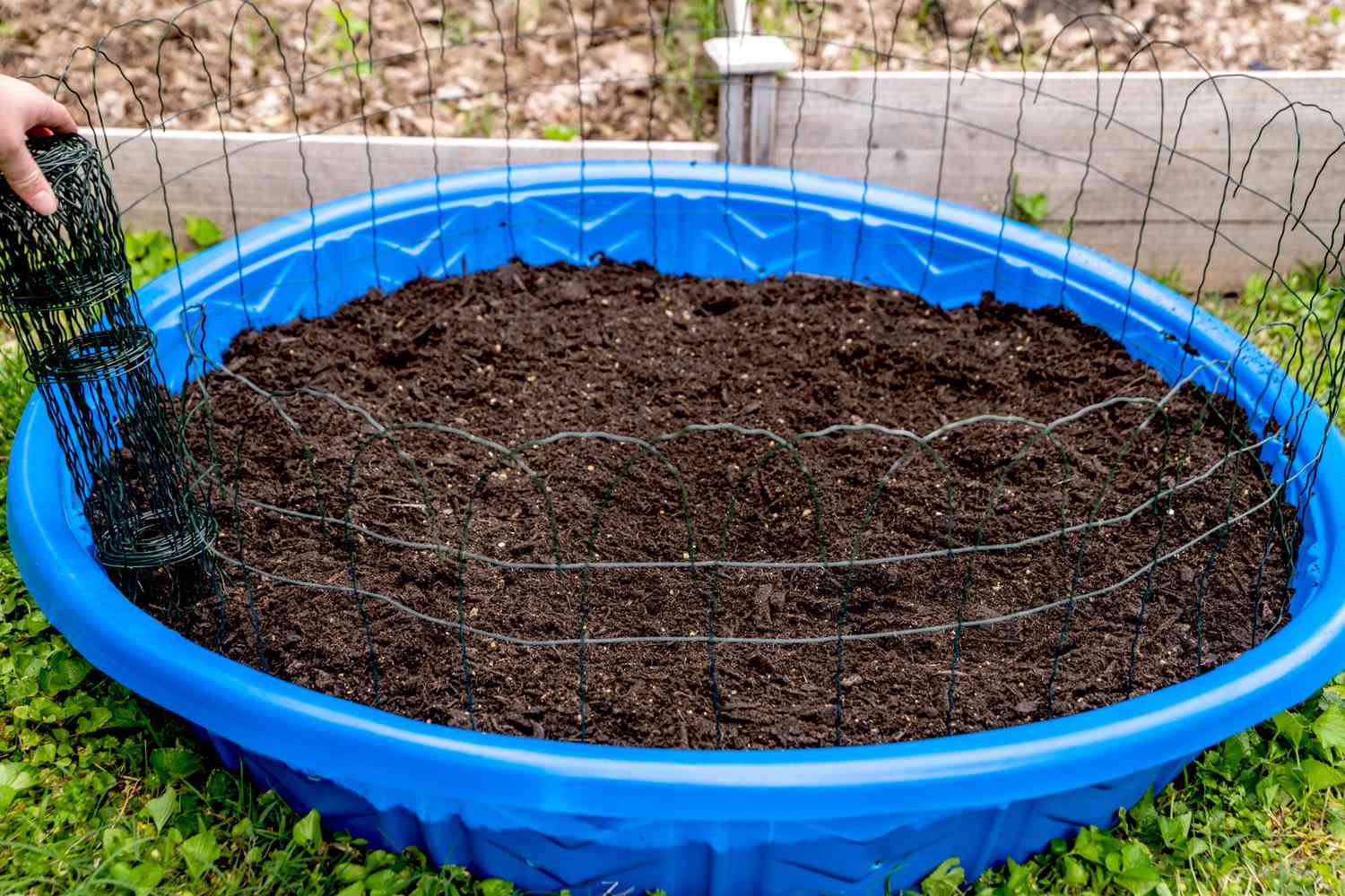 Metal fencing added around kiddie pool with smooted out soil