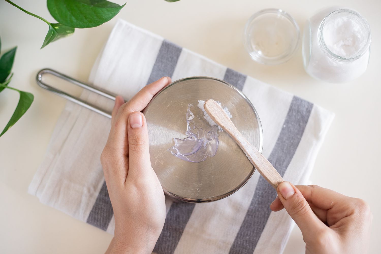 Geschmolzenes Plastik am Boden einer Metallpfanne mit Backpulver und Zahnbürste entfernt