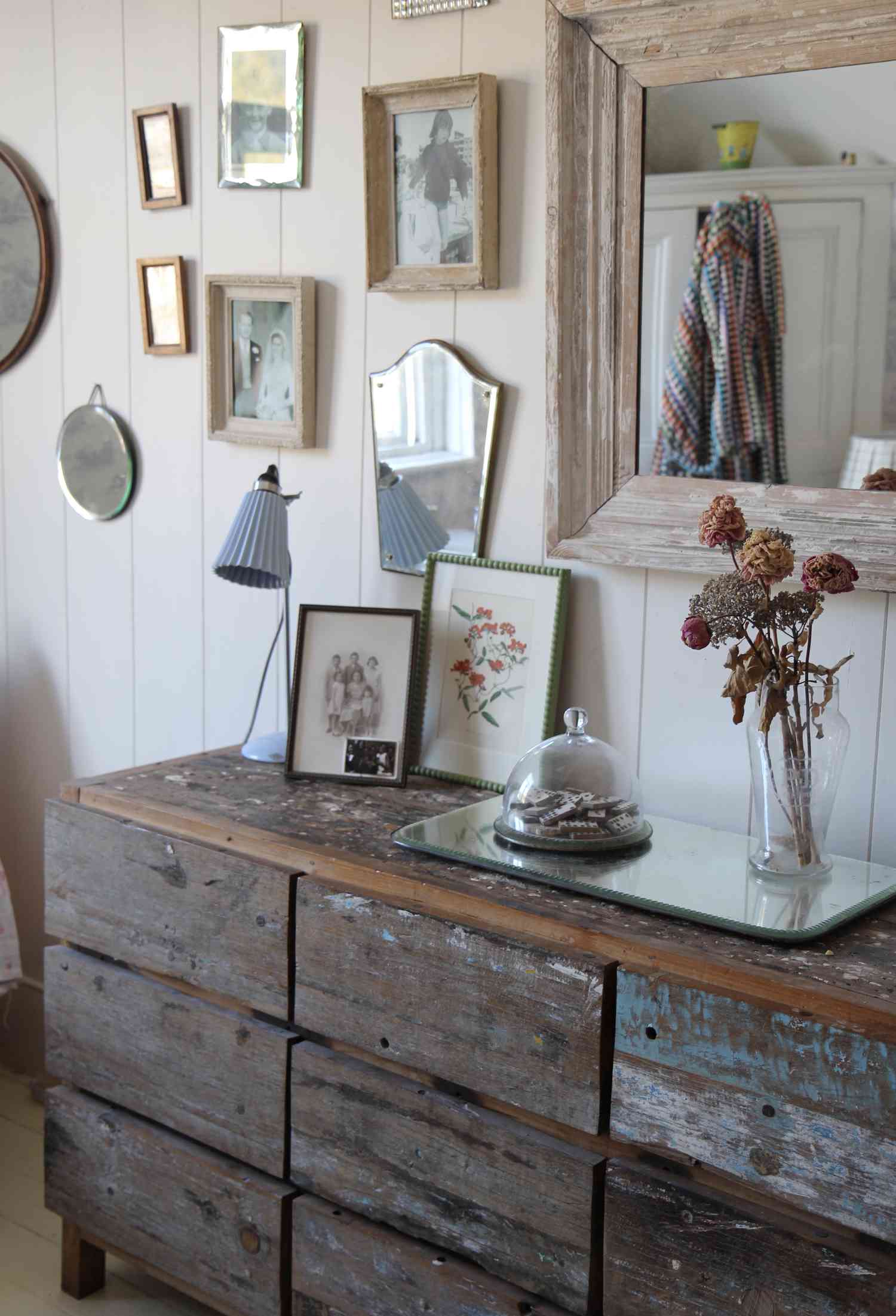 Commode de style cottage avec de l'art dépareillé sur le mur au-dessus. 