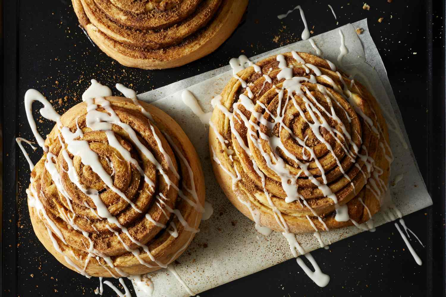 Eine Aufnahme von Zimtrollen mit Zuckerguss von oben.