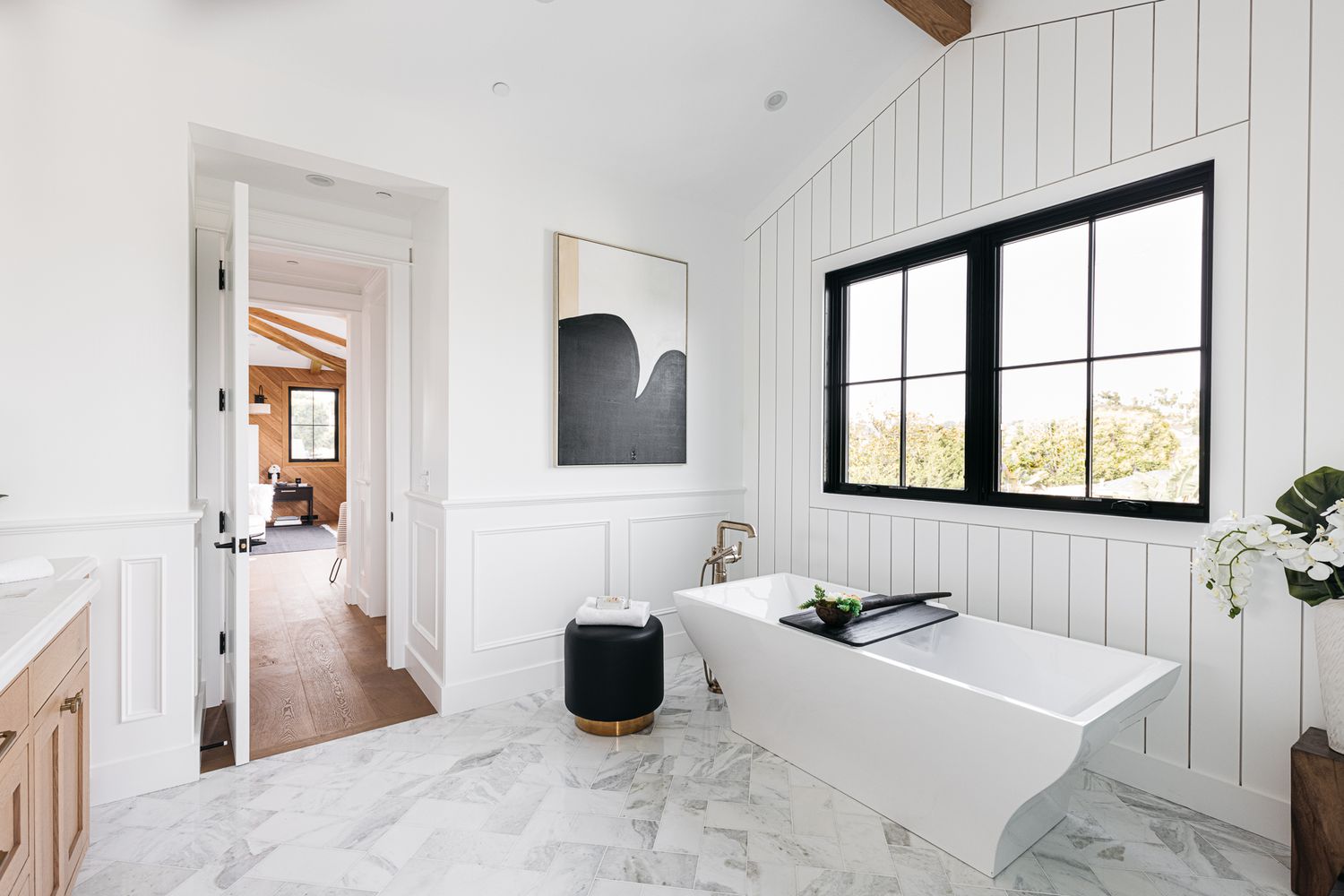 Brightly-light bathroom with marble flooring, white walls and black decor