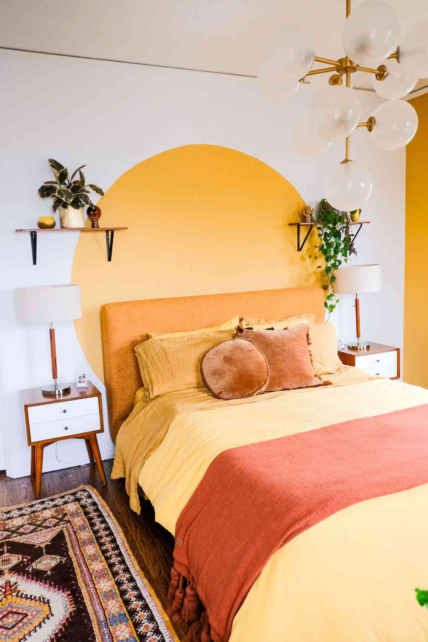 Schlafzimmer mit gelbem Wandbild auf weißer Wand, gelbe Bettwäsche, schwebendes Regal mit Pflanzen