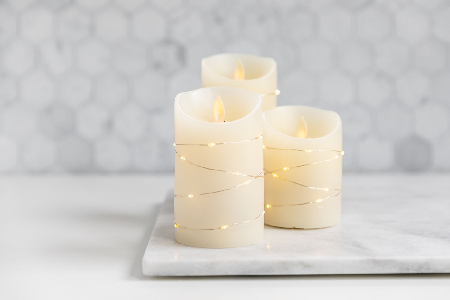 Três velas sem chama envoltas em luzes de fada