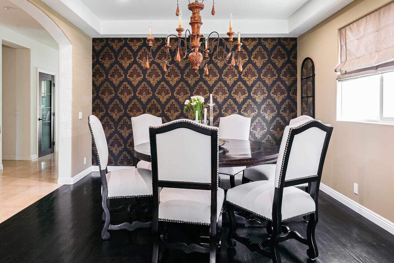 Sala de jantar elegante com papel de parede com padrão preto e marrom atrás de cadeiras brancas e pretas