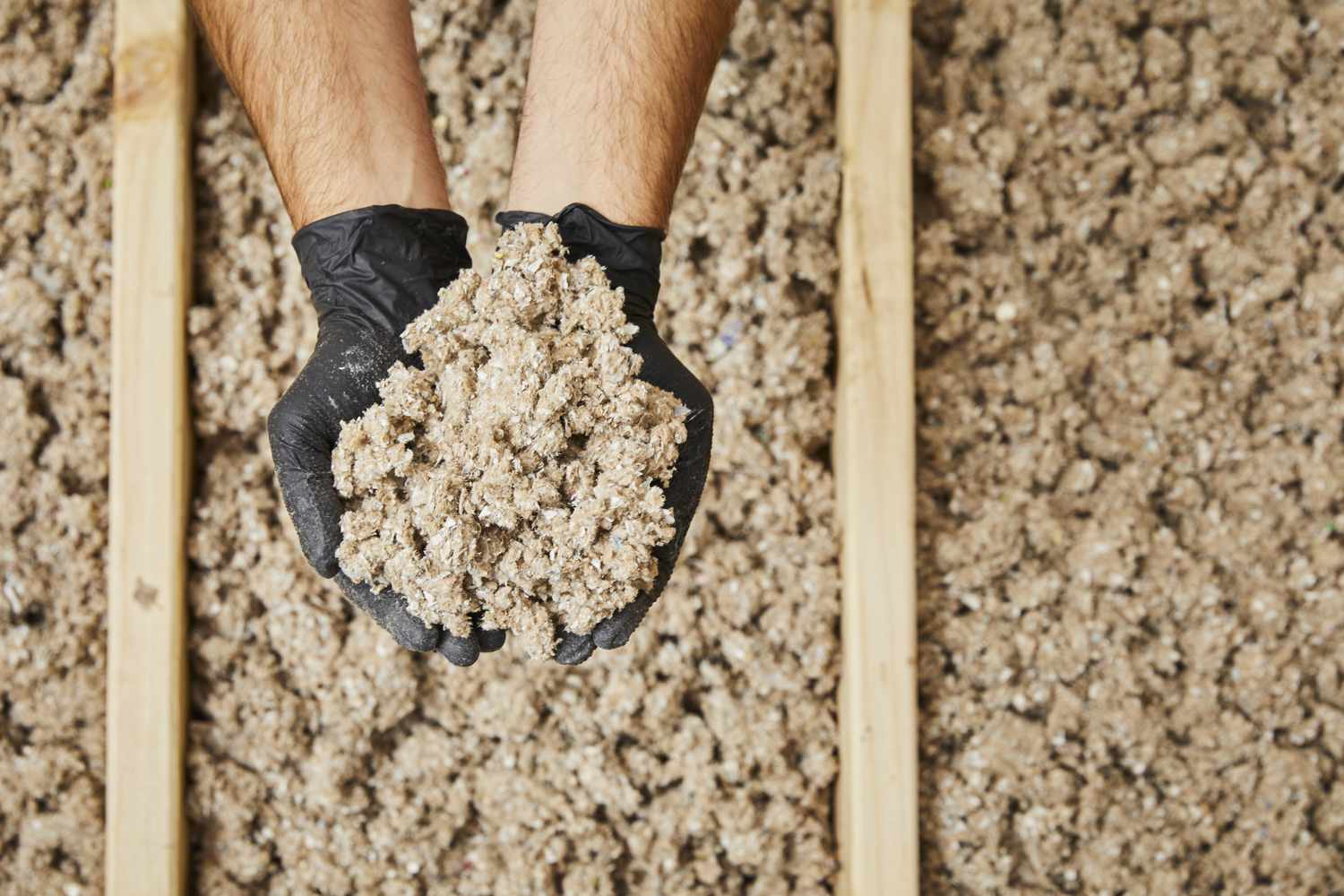 Hands holding a pile of loose-fill cellulose insulation