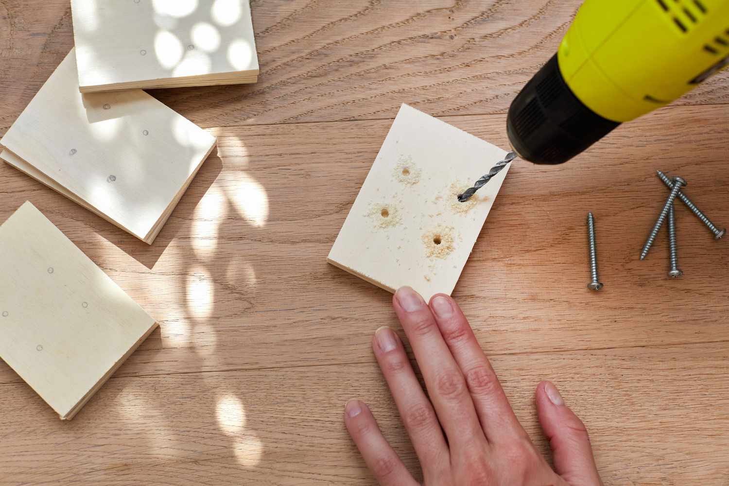 Electric drill adding holes to plywood pieces