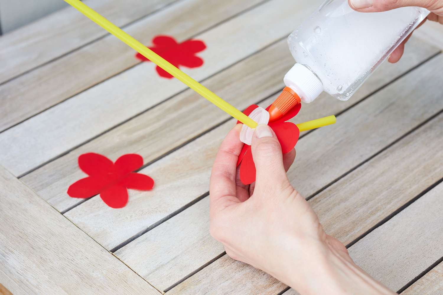 Geschnittene Blume auf Flaschendeckel geklebt, gelber Strohhalm läuft durch