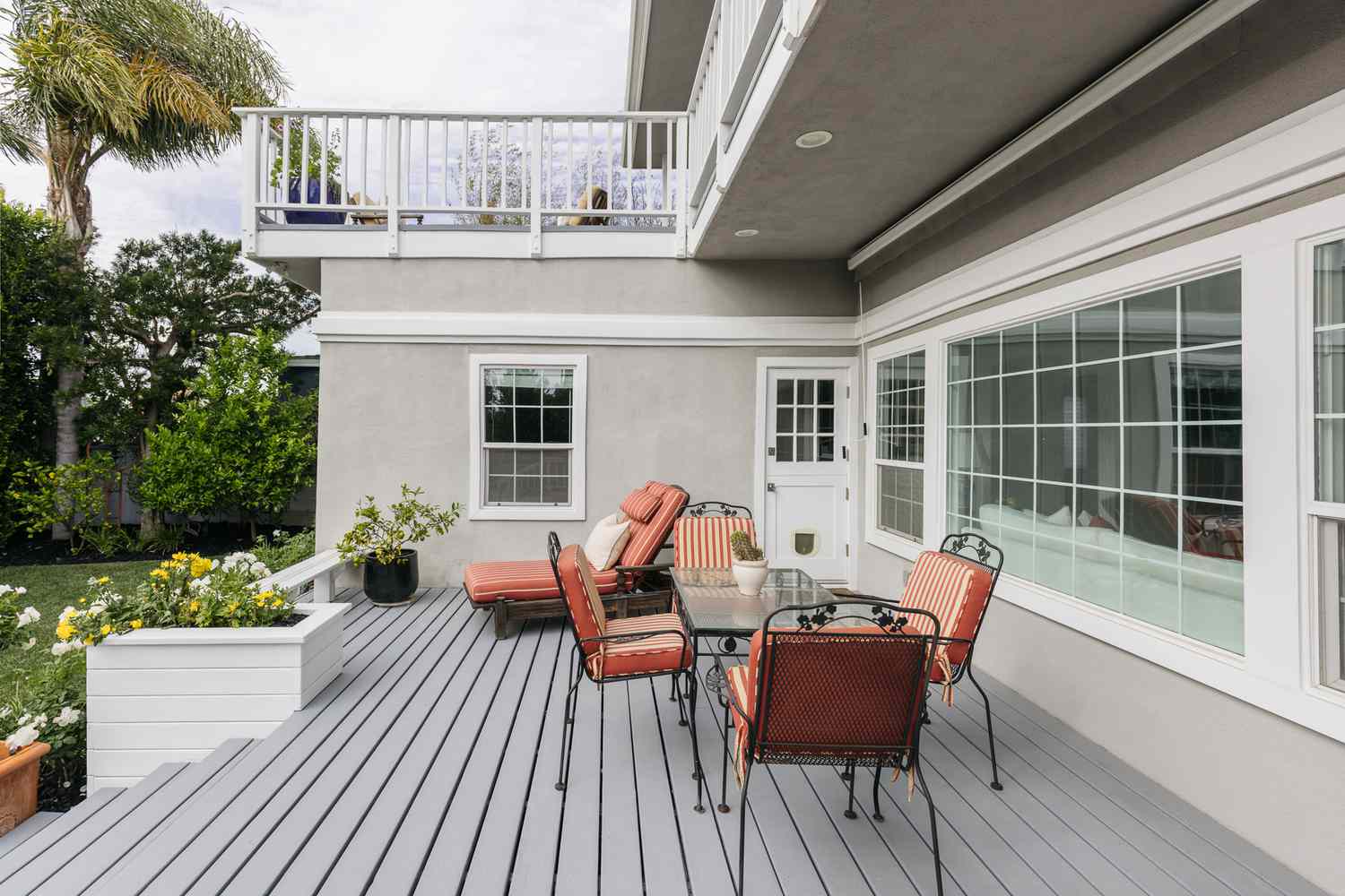 Cubierta exterior con suelo gris y muebles metálicos cubiertos con cojines naranjas