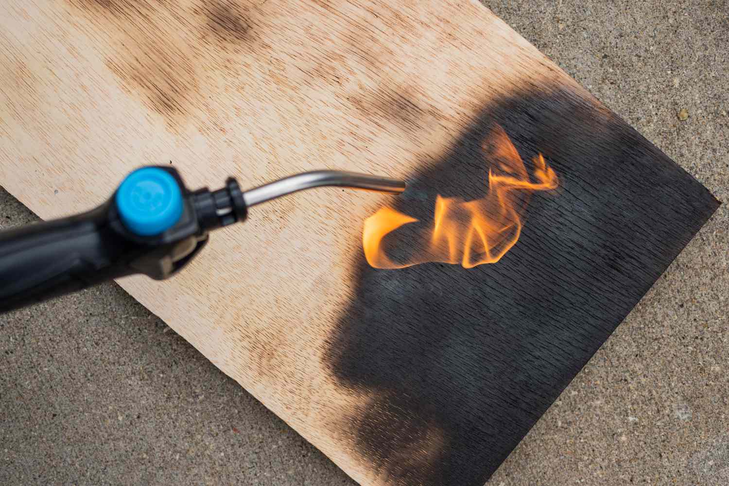 Blow torch putting flame on wood for burnt finish