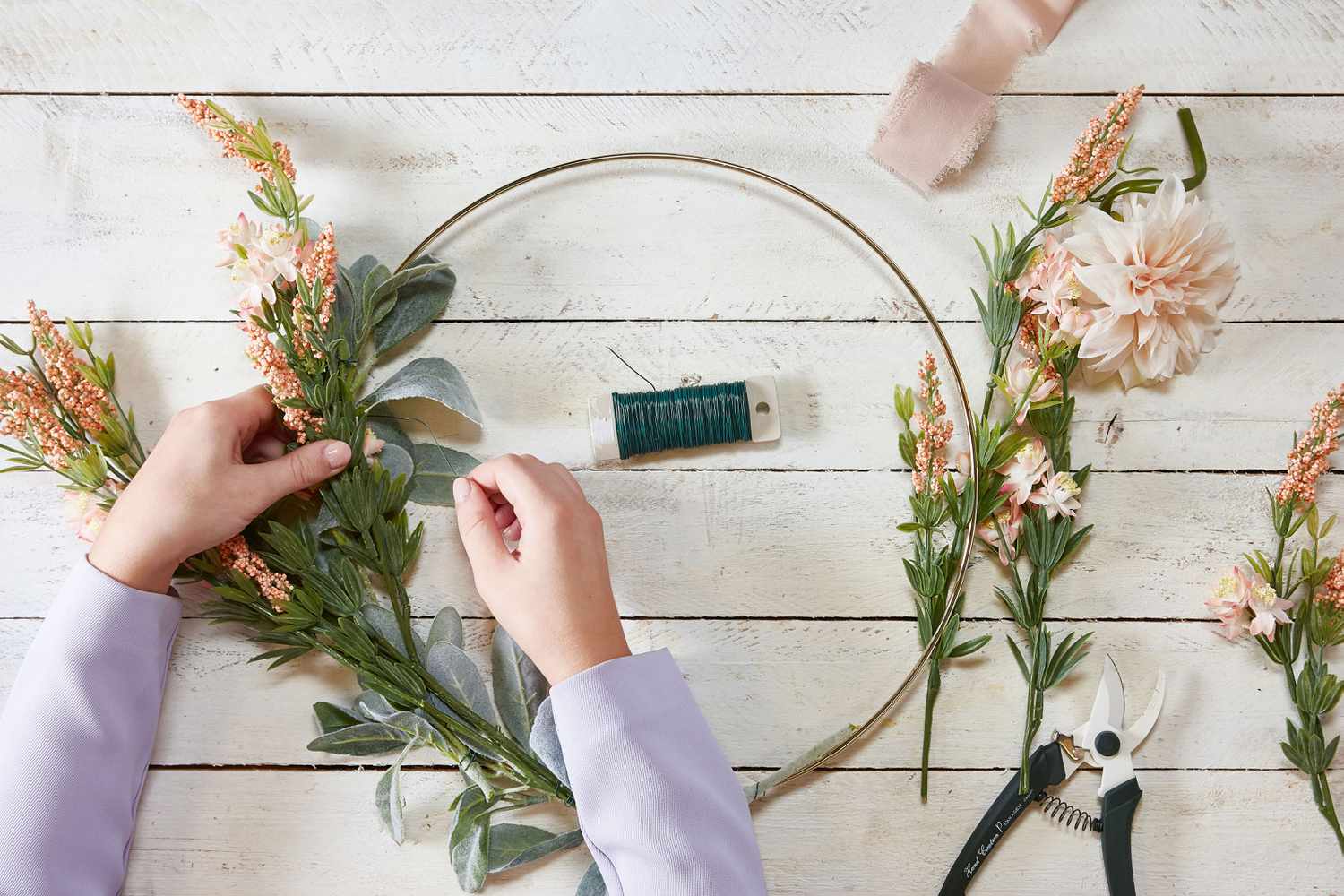 Hands placing filler flowers on hoop