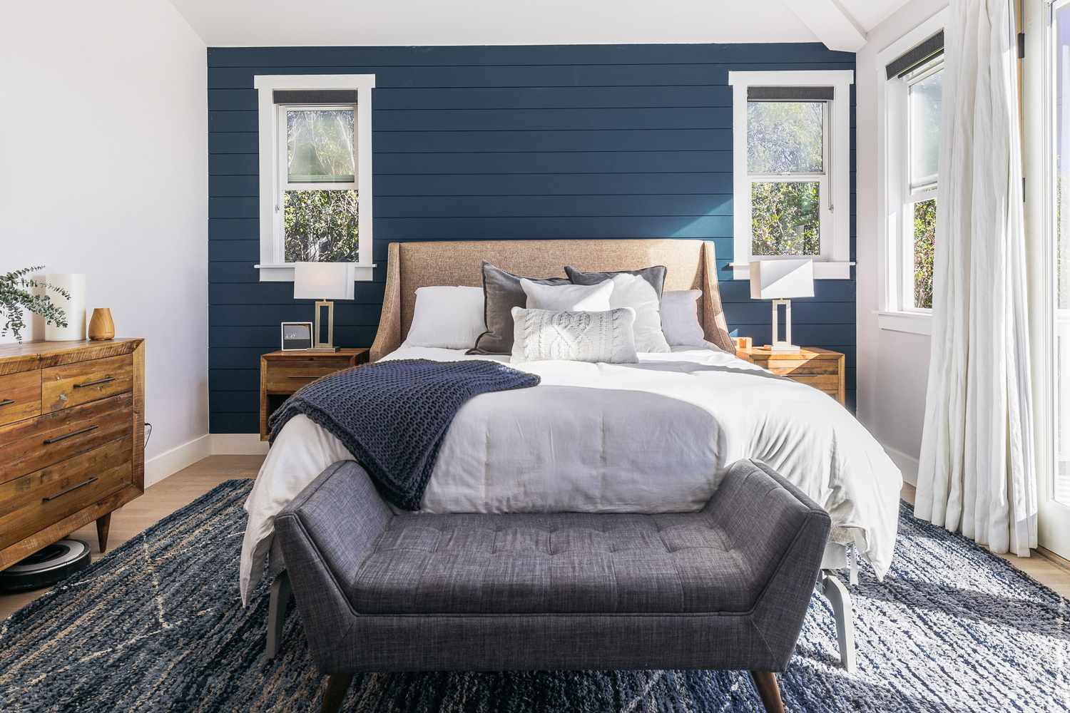 Moody bedroom with blue shiplap walls, blue and gray bedding and gray bench in front
