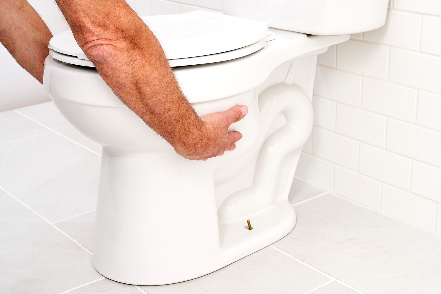 Toilet pulled from floor while holding each side of bowl