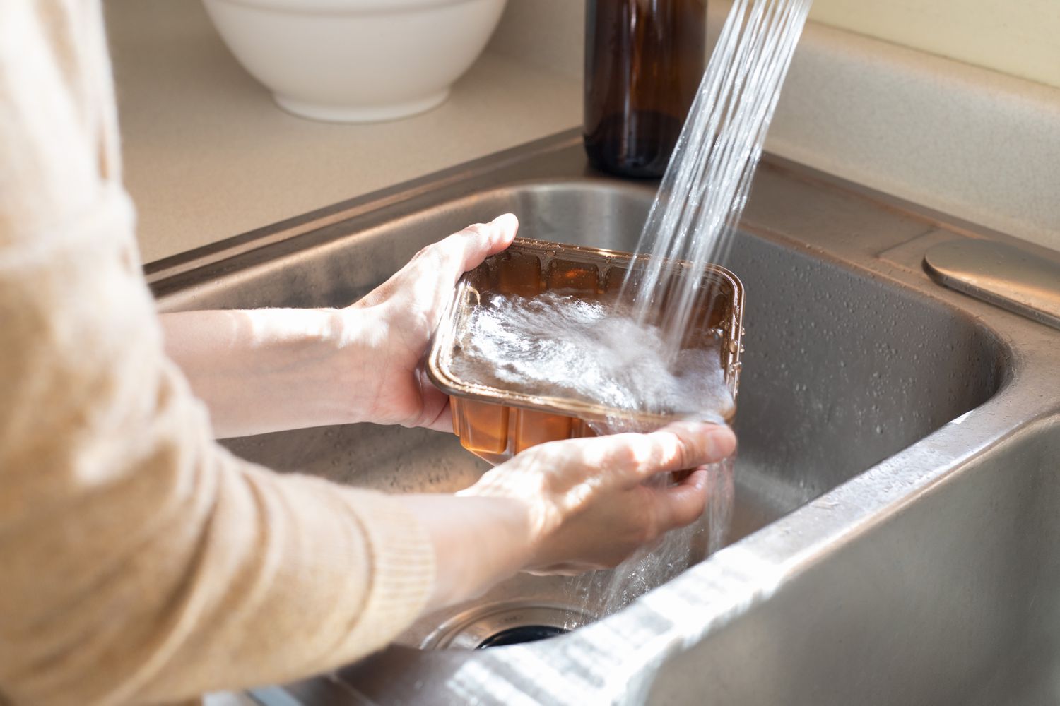 Recyclingbehälter wird im Waschbecken gespült, um Ameisen zu vermeiden