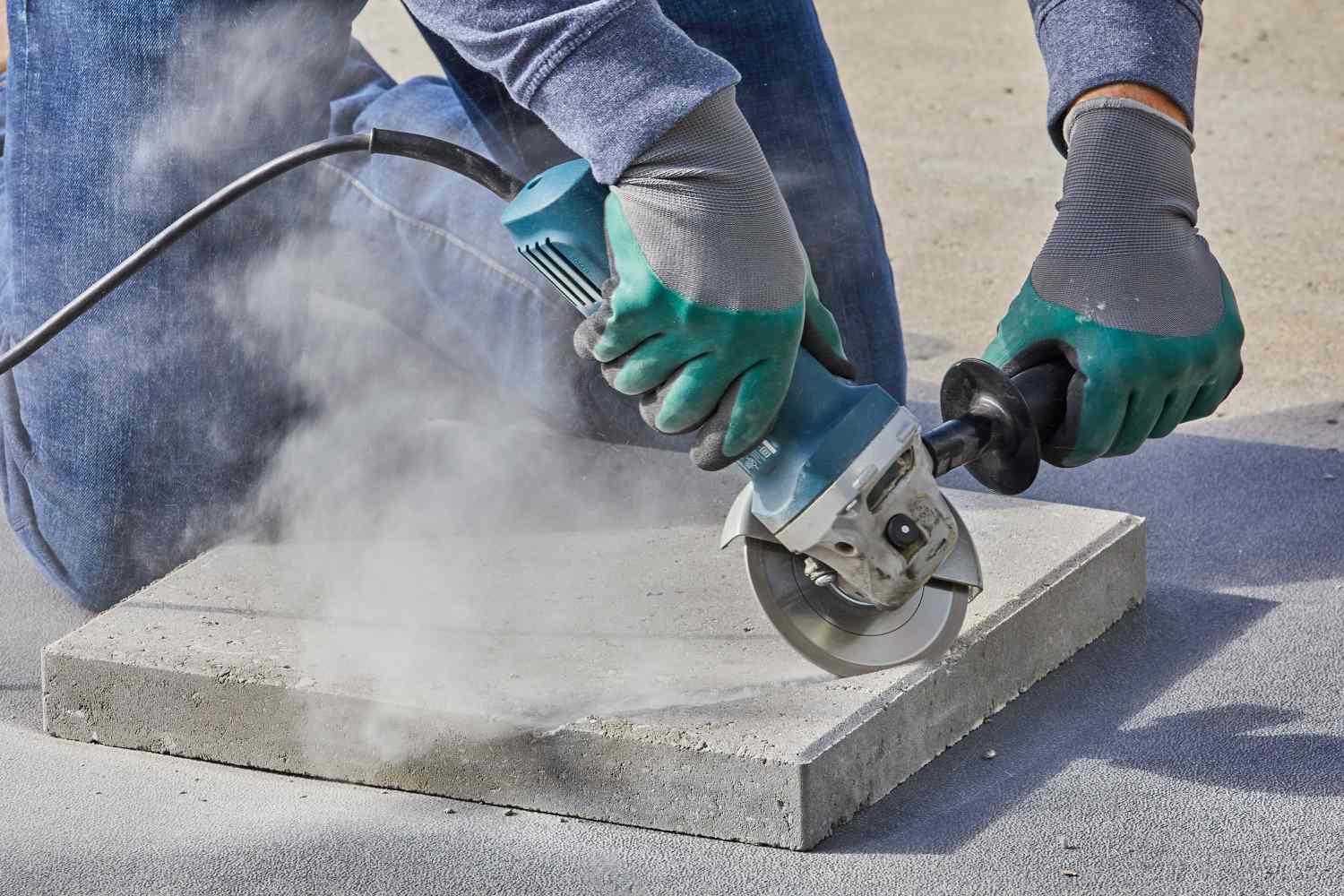 Person, die einen Pflasterstein mit einer Handsäge schneidet