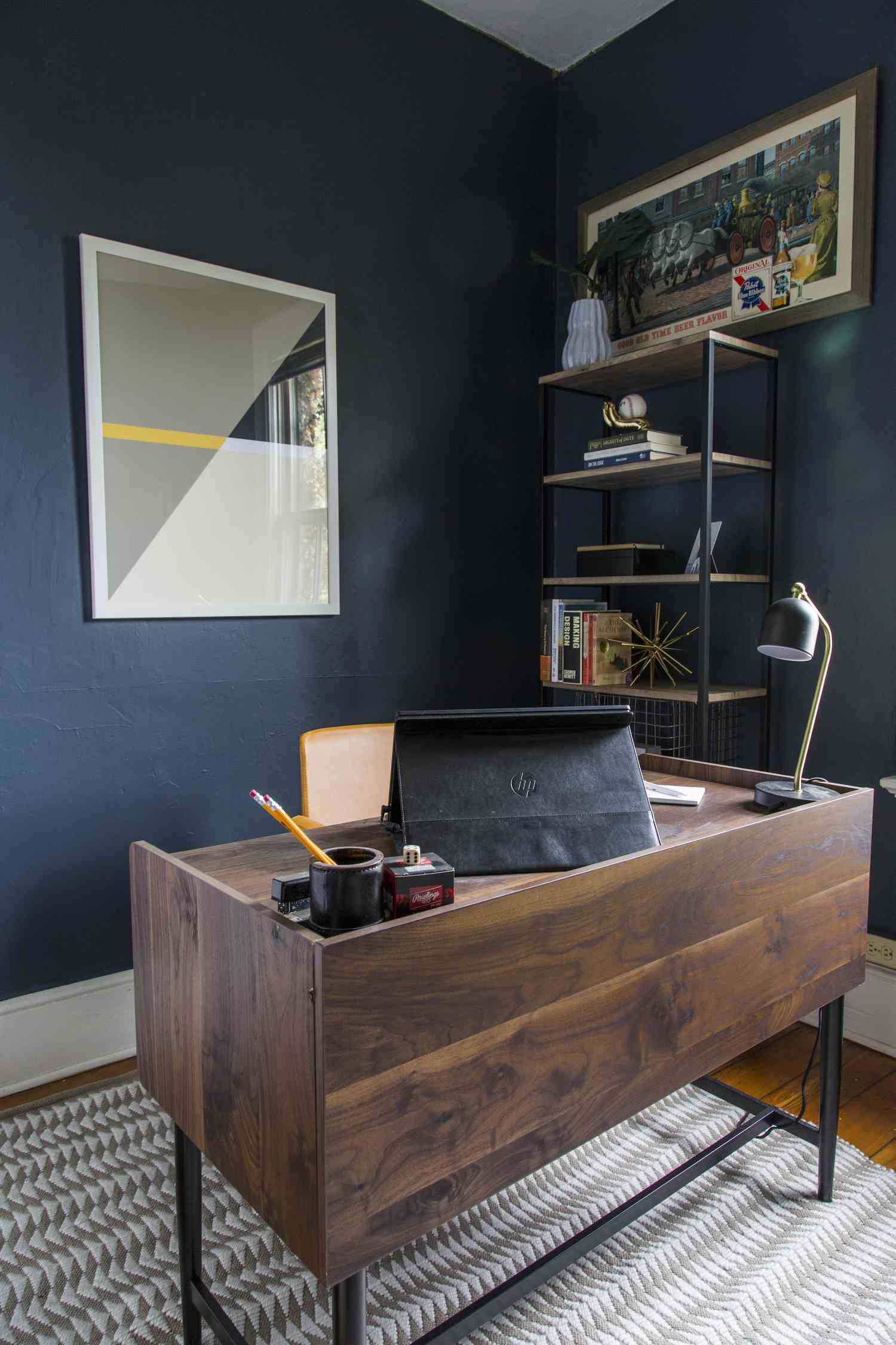 Büro mit dunklem Holzschreibtisch und dunkelblauen Wänden.