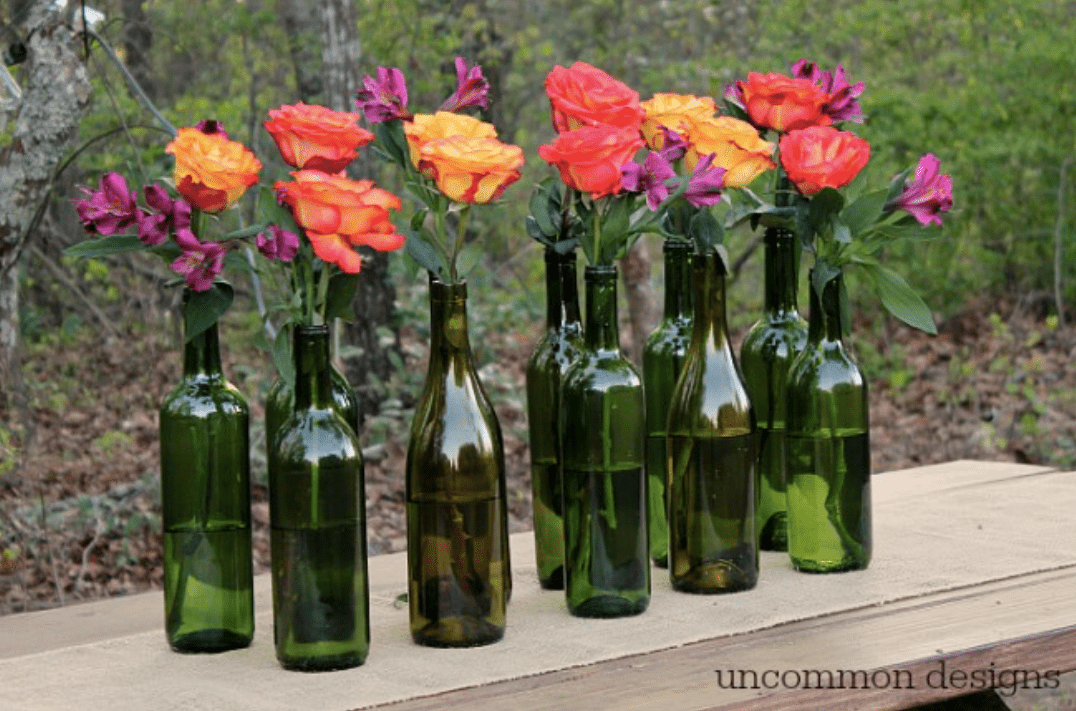Weinflaschen mit verschiedenfarbigen Rosen darin 