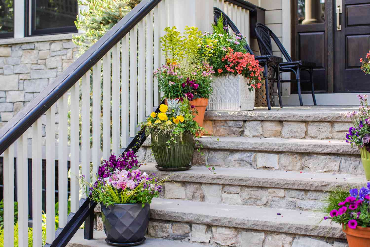 Topfpflanzen und bunte Blumen auf den Steinstufen vor der Haustür