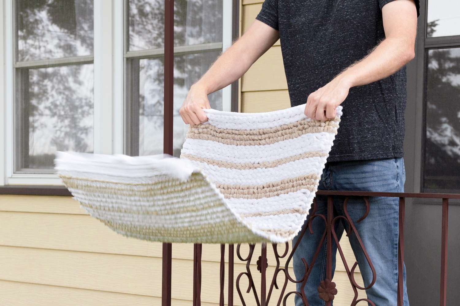 Person shaking a rug outdoors