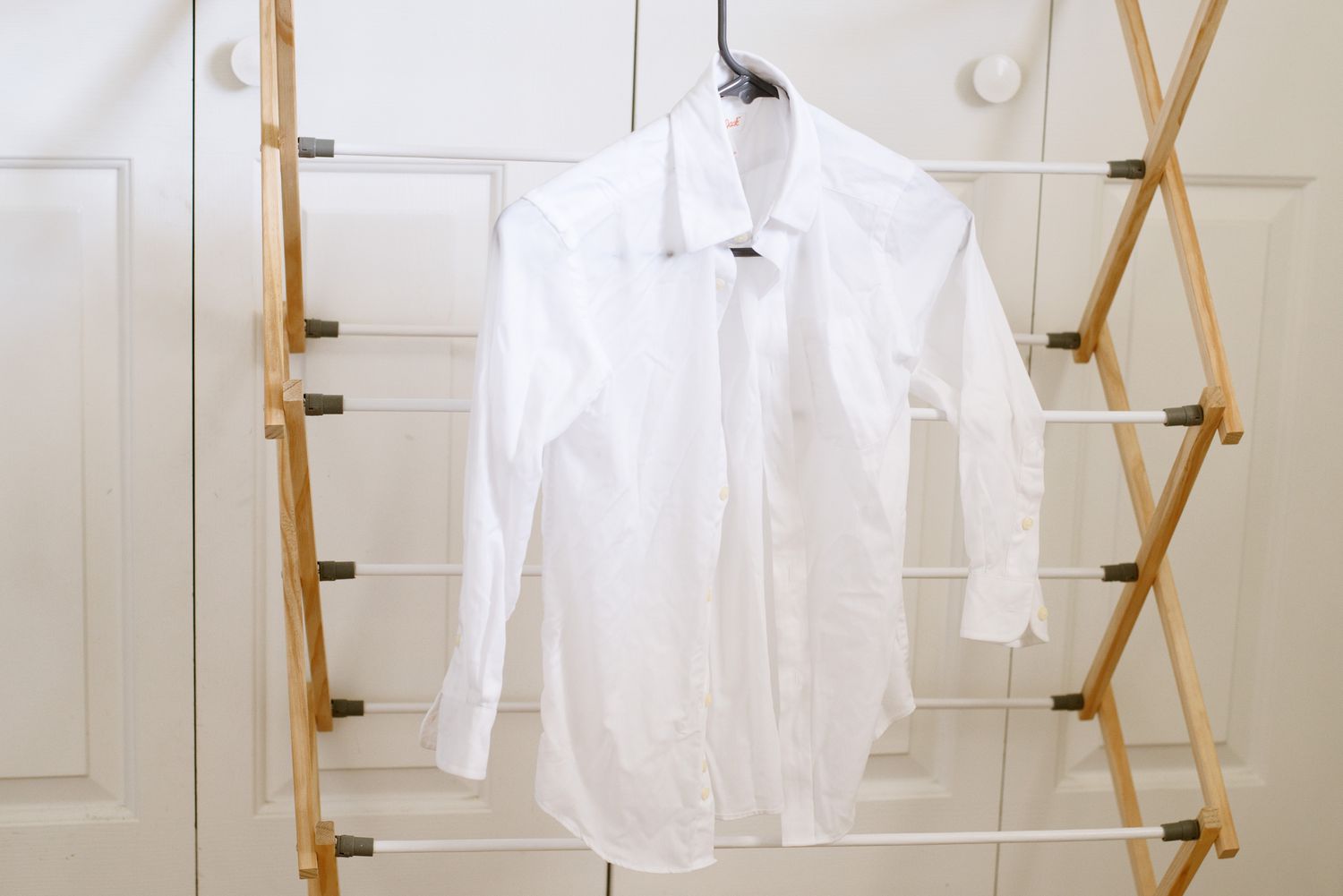 Weißes Button-Down-Hemd zum Lufttrocknen auf den Wäscheständer gehängt