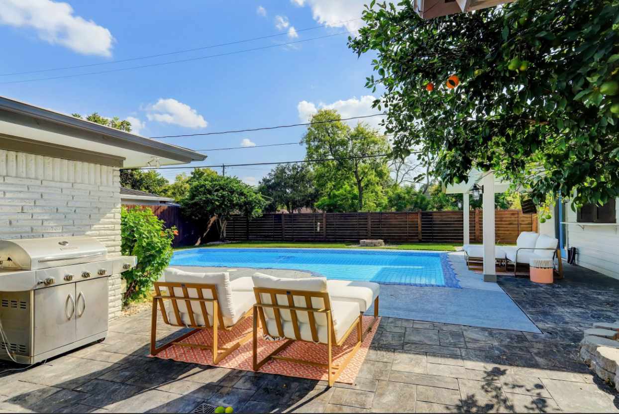 Uma piscina no quintal com pavimentação de pedra e uma área de estar