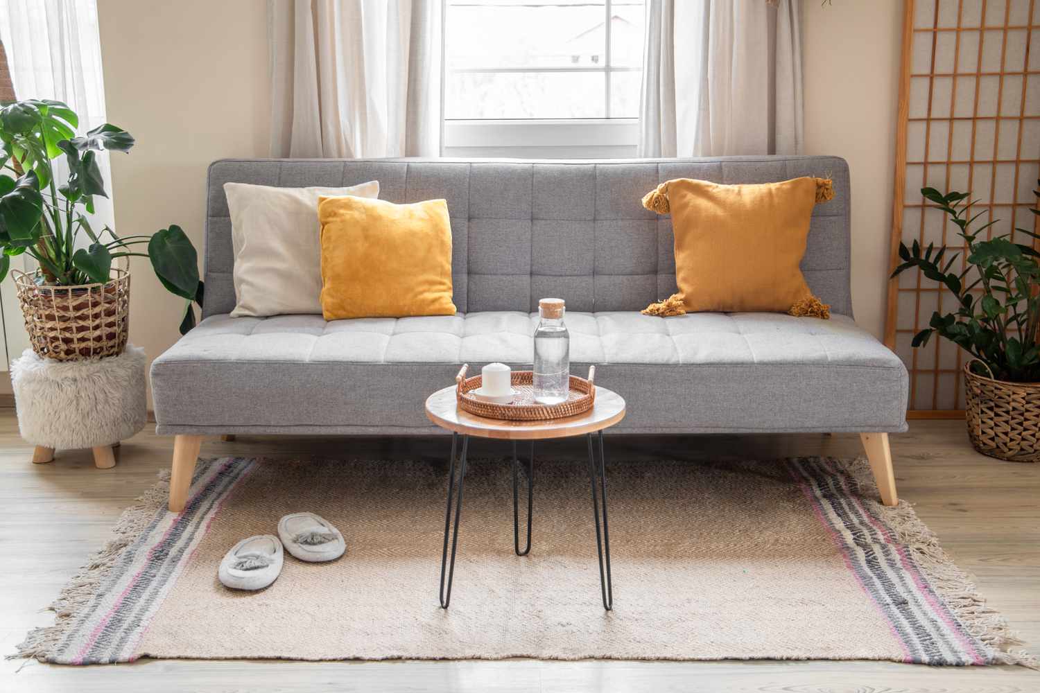 Salon avec canapé gris sur tapis à franges tan