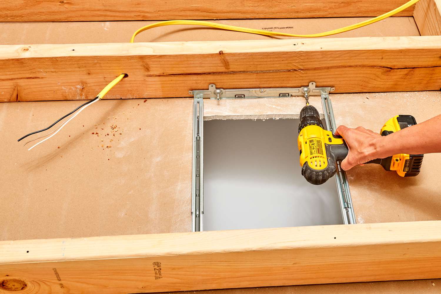 Suspension brackets drilled to wood joists to house exhaust fan 