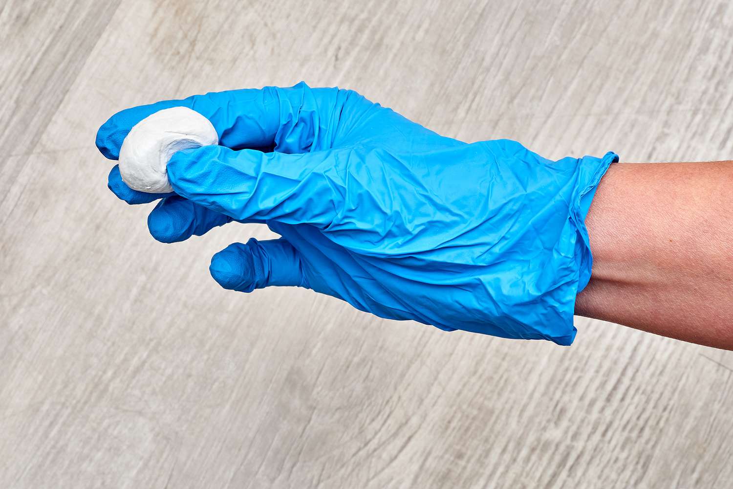 Reparatur-Epoxid mit blauen Handschuhen zu einer kleinen Kugel geformt