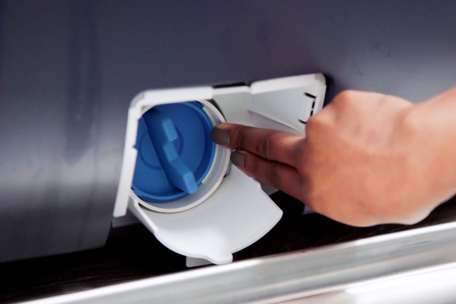 Filtro de drenagem azul empurrado de volta para a lavadora com os dedos conectados ao sistema de fossa séptica